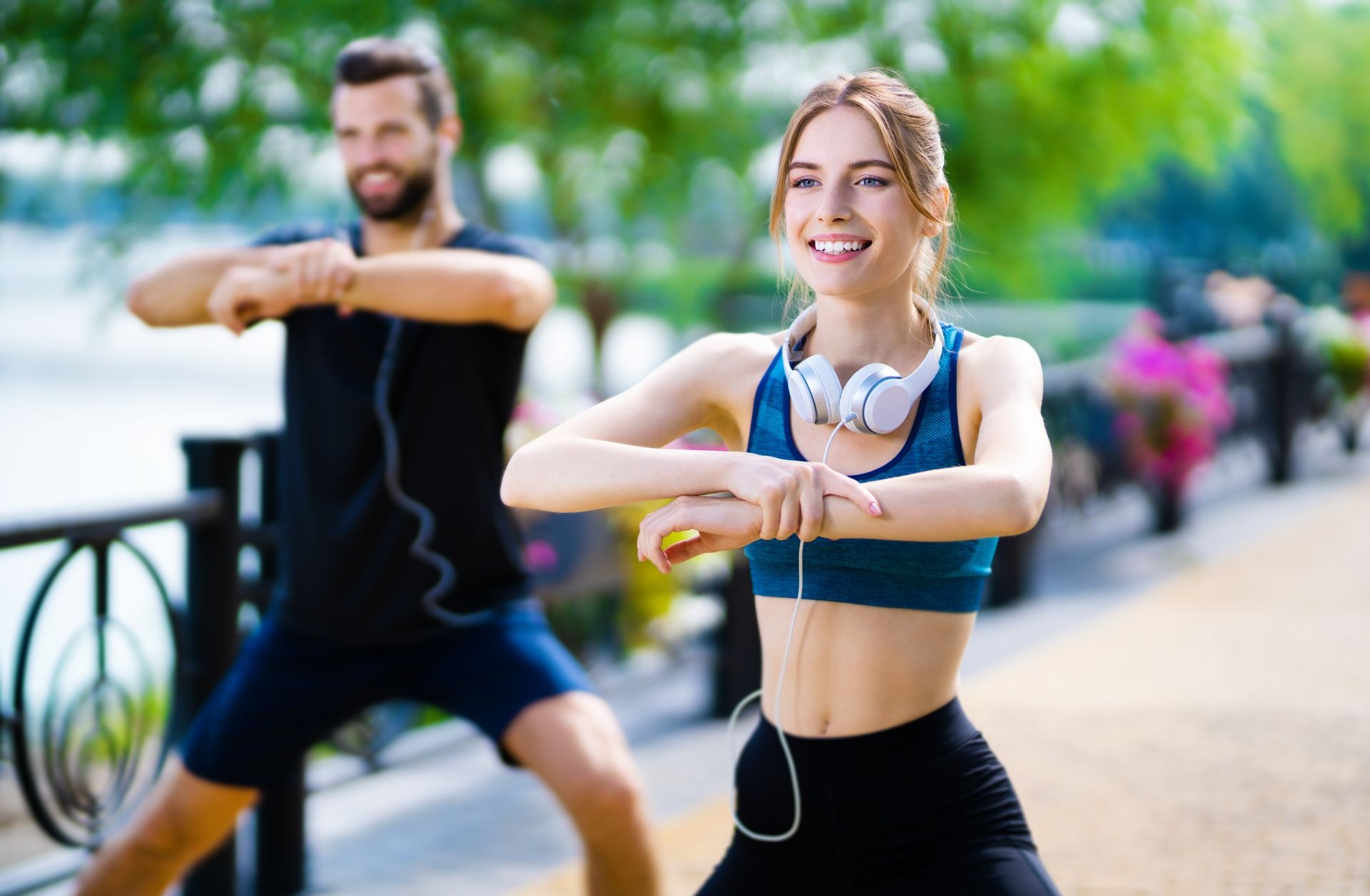 Young happy couple, or woman training with instructor, doing fit exercises together, outdoors. Fitness, sport workout and healthy lifestyle concept. 